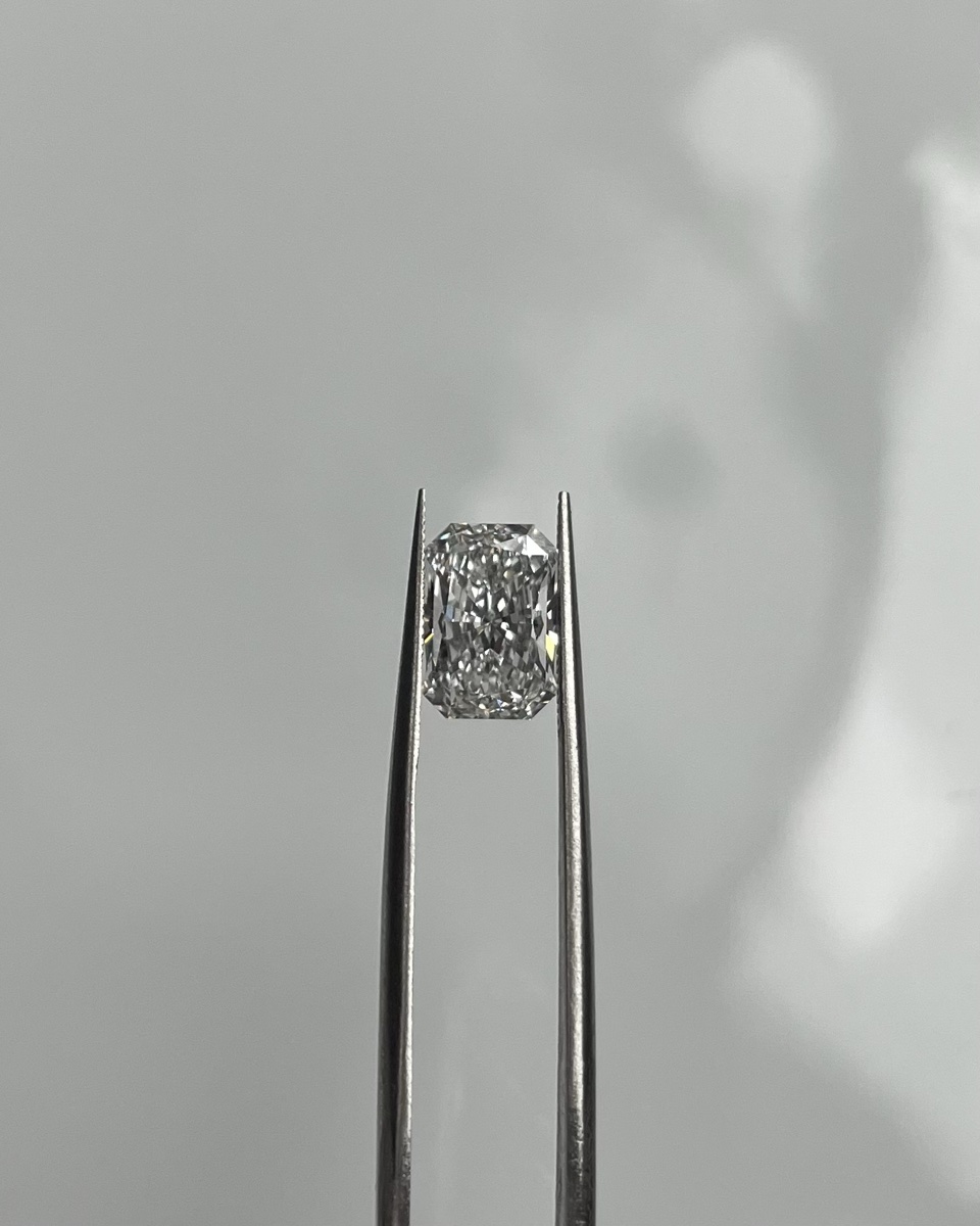 Macro photograph of a loose diamond held with tweezers, showing its facets under close inspection